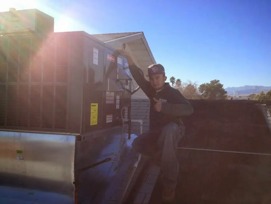 HVAC technician performing HVAC Inspection on a rooftop unit in Becker